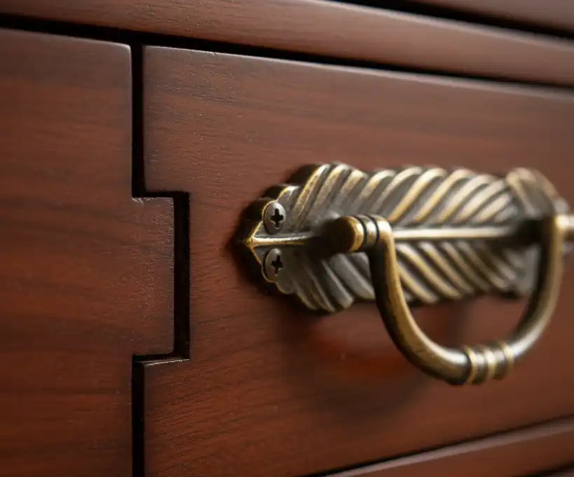 Close-up of mortise-and-tenon wood joinery and custom brass drawer pulls on a Tommy Bahama chest