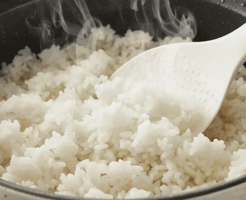 Step 5 - Fluffing the cooked rice with a silicone rice paddle after resting